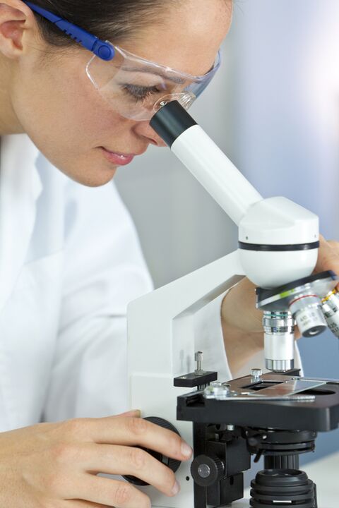 mujer mirando a través de un microscopio
